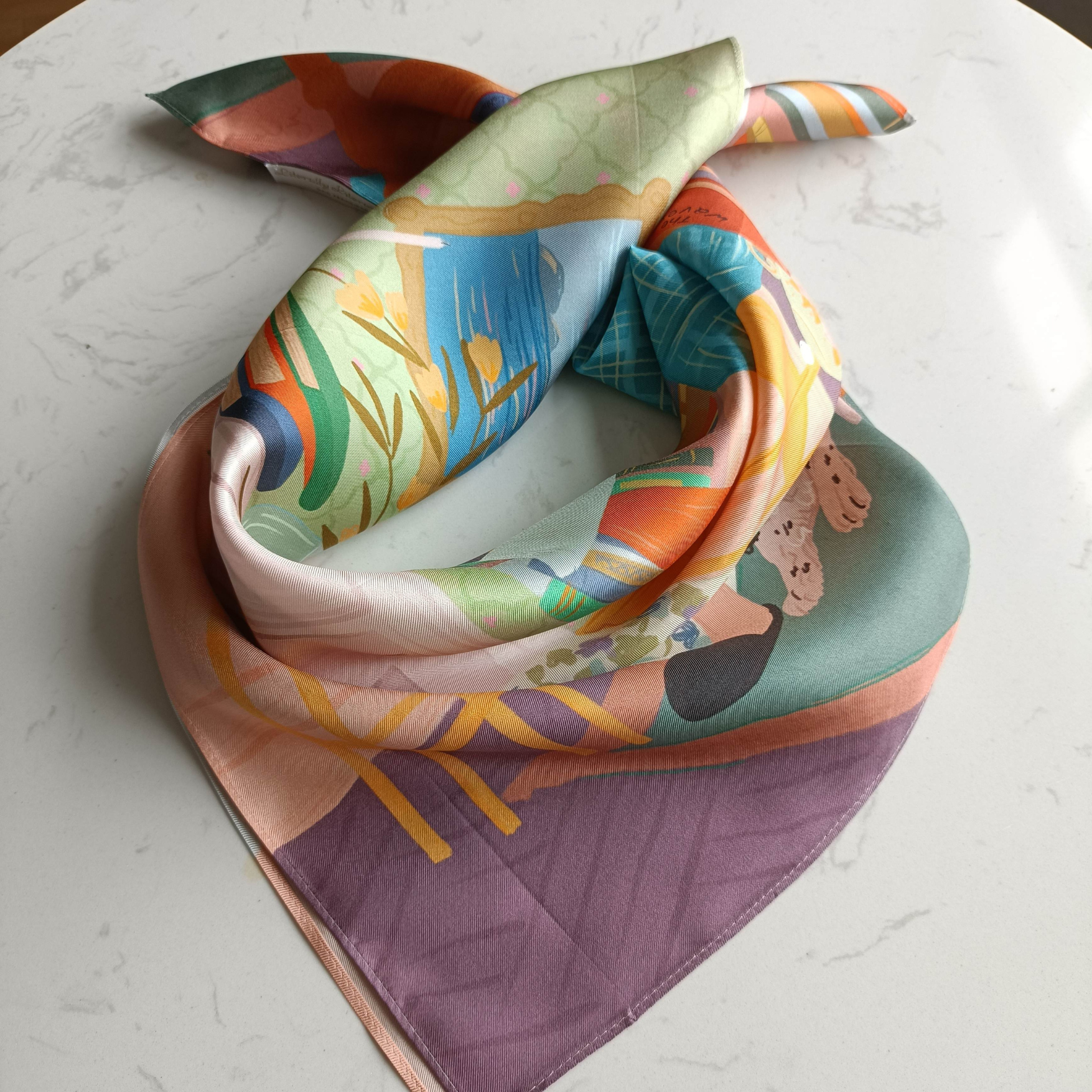 Silk scarf featuring a portrait of Virginia Woolf sitting in an armchair surrounded by books, with a dog at her feet